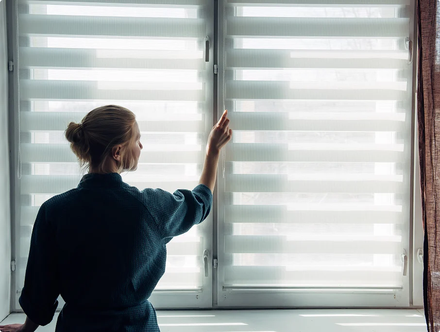 Frau bedient moderne Doppelrollos am Fenster
